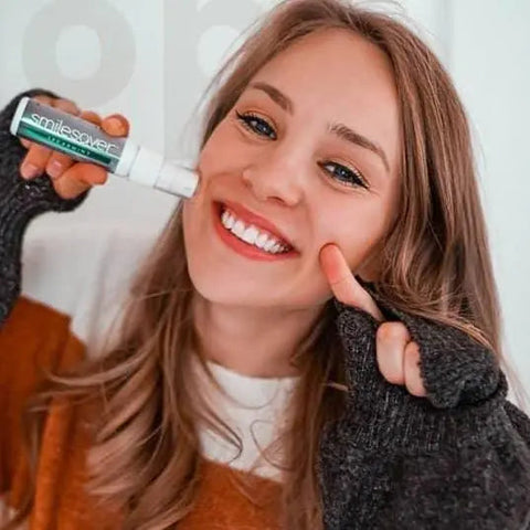 happy woman with nice teeth holding mouthpiece cleaner